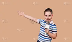 男孩正在录音棚里录他的歌。唱歌的孩子拿着麦克风