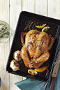 Roast chicken, garlic, rosemary and lemon in a roasting pan with a carving knife and fork, studio... by Radius Images on 500px