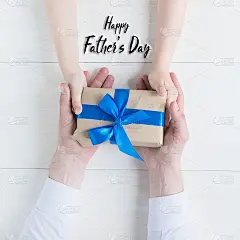 祝您父亲节快乐。贺卡。礼物在女儿和父亲的手中在一个白色的背景。我爱你，爸爸。爱和健康的家庭。