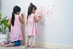 亚洲小女孩喜欢在客厅的白墙上作画。可爱的小朋友们在家里愉快地画画、涂色，享受着节日的创意活动。照片摄影图片