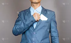 近处有吸引力的商人手持空白白色模拟卡插入他的西装口袋。