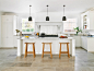 Photo of a medium sized traditional l-shaped kitchen in London with shaker cabinets, white cabinets, stainless steel worktops, metallic splashback, black appliances and an island.