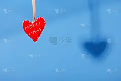红色手工制作的心形圣诞玩具挂在蓝色的背景下。复制空间,最小