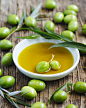 Fresh green olives with leaves and olive oil on wooden backgroun