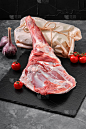 Raw lamb leg on marble cutting board. Dark backgro