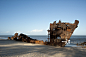 Rusted shipwreck on beach.
