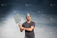 一个戴着锡箔帽的古怪男人不敢用手去抓。睁大眼睛和嘴巴，举着蓝色背景的罢工海报。