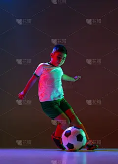 男孩的全长肖像，孩子，足球运动员在运动孤立的梯度背景在霓虹灯。运球