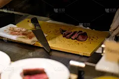 在豪华的晚宴上，近距离的牛排片和刀放在木板上