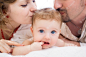 Happy family, mother, father and daughter resting on the white bed Premium Photo