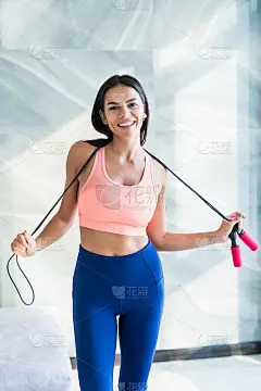 Fit快乐的女人在运动服抱着跳绳在家里明亮的房间