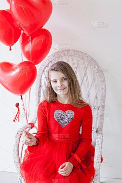 漂亮时尚的小女孩在节日里拿着心形的红色气球