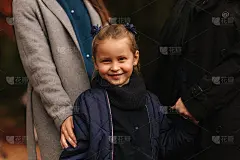 森林里小女孩的画像。妈妈，爸爸和姐姐的背景。年轻的家庭在秋天的公园