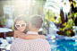 Father carrying daughter wearing heart shaped sunglasses by swimming pool by Caia Images on 500px