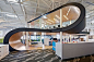 This may contain: an office building with a spiral staircase in the center and desks on both sides