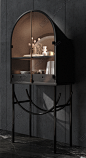 a black cabinet with glass doors and shelves on the top, in front of a gray wall