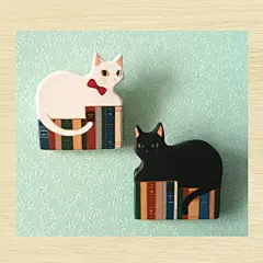 洋書と猫のブローチ : 並んだ本の上に乗った白猫と黒猫のブローチです。販売価格は1点の値段です。ご注文の際はご希望のブローチを備考欄にご記入ください。 白猫or黒猫☆現在こちらの作品は受注制作にてお作りしております・制作にお時間を頂戴いたしますが大切に作らせていただきます(1週...