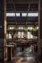 Restaurant and bar with brick walls and high exposed ceiling and sky lights.
