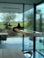 a wooden table with a glass window in the background and a surfboard hanging from it's side