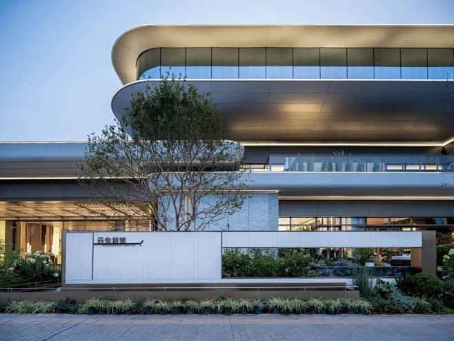 西安中粮悦著云朗04社区大堂在建筑形体上采用中心对称式构图， 强调归家仪式感，主入口两侧采用内凹环抱弧形墙面，勾勒出主入口空间。入口空间采用6-花瓣网