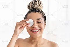 年轻漂亮的非洲裔美国女性用棉垫遮盖她的眼睛隔离，美化概念，娇养，年轻化和皮肤护理