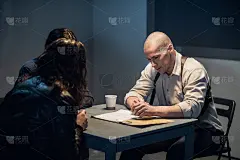 在审讯室里，侦探和警官正在和罪犯谈话