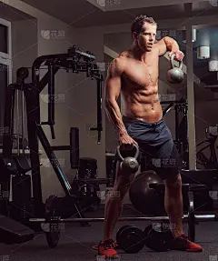 英俊的肌肉赤膊健美男子做锻炼三角肌壶铃在健身房。