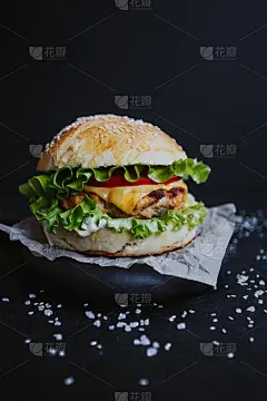 美味的自制汉堡，配上鸡排，生菜，番茄，芝士和酱汁。在黑色背景的木板上