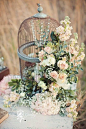 birdcage overflows with a gorgeous flower arrangement for rustic wedding: 