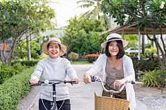 快乐的老年亚洲妇女骑自行车与女儿在公园，健康保险和老年人照顾的概念