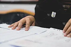 在大学教室里，老师检查课桌上的答题纸文件。参加考试，写考场学生的作业作业文件