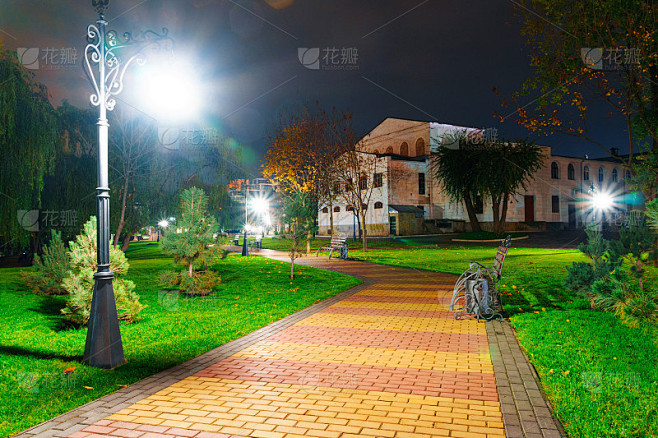秋天的城市公园晚上，黄叶树，路灯和长椅