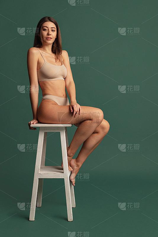 年轻美丽苗条的女孩在裸色内衣坐在高椅子上...