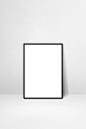 Black picture frame leaning on a white wall. blank mockup template Premium Photo