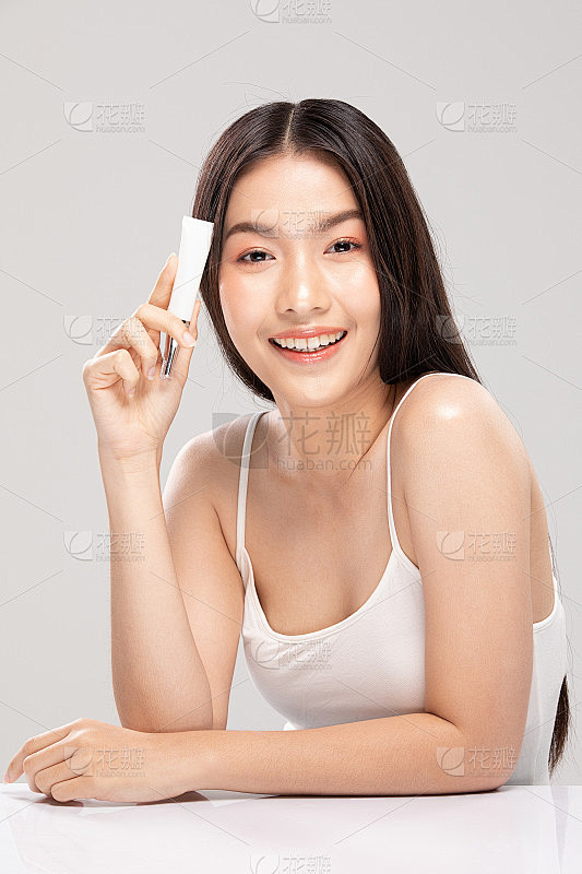 美丽年轻的亚洲女人抱着奢侈的白色清洁管微...