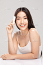 美丽年轻的亚洲女人抱着奢侈的白色清洁管微笑感觉如此快乐和愉快与健康清洁和新鲜的皮肤，孤立在灰色的背景