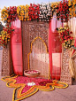 The main entrance to this Indian wedding's event hall is a gorgeous pattern that combines classic customs with a contemporary look. Perfect with a marigold garland and colorful curtains.