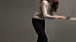 Fashionable woman leaning over a table typing on the Graphite Gold Surface Laptop.