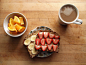 navel oranges slices, sprouted grain toast with peanut butter and banana on one slice and almond butter and strawberries on the other, coffee with soy milk