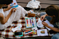 Two people sitting on a blanket painting pictures