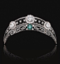 EMERALD AND DIAMOND TIARA,  CIRCA 1910.  The upper tier of open work trellis design millegrain-set throughout with rose diamonds, and decorated with three flower head cluster motifs set with circular-cut diamonds, the lower tier of foliate and meander des