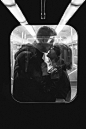 Grayscale Photo of Man Kissing Woman's Nose While Standing Inside a Train