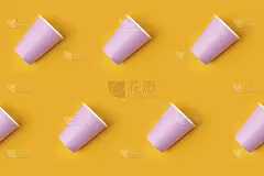 图案由粉红色的纸杯对角线排列在黄色的背景。生日派对庆祝抽象时尚宝宝送礼概念。极简风格