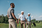 young multiethnic golf players looking away while standing on pitch