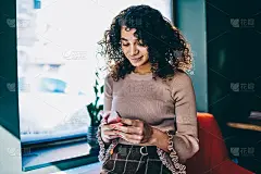 快乐的嬉皮女孩使用手机搜索信息阅读网页上的积极新闻，微笑的女人享受通过智能手机应用在wifi区与粉丝