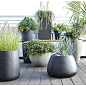 Handsome planters play the supporting role with style, showcasing greenery indoors or out. Curved wide-mouth containers in neutral charcoal grey are cast from an innovative blend of stone, plastic and cement that adds strength while reducing weight.: 