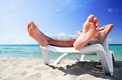 一名年轻人在海滩的沙滩床上晒日光浴