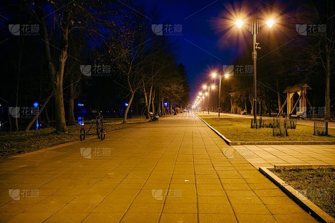 夜晚的城市公园。木凳，街灯和公园小巷。铺着瓦片的路在夜晚的公园里挂着灯笼。晚上在公园的长椅上。在晚上