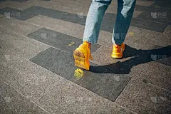 斯凯奇人穿着黄色的鞋子踩在黄色油漆上留下了痕迹。