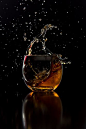 This may contain: a wine glass filled with liquid on top of a table next to a black background